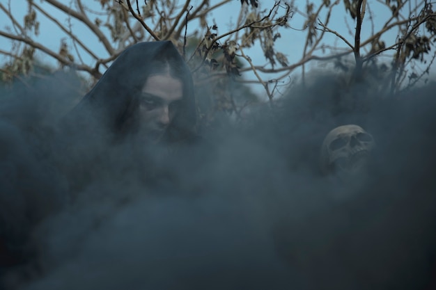 Бесплатное фото Черная ведьма, покрывающая лицо мага и череп