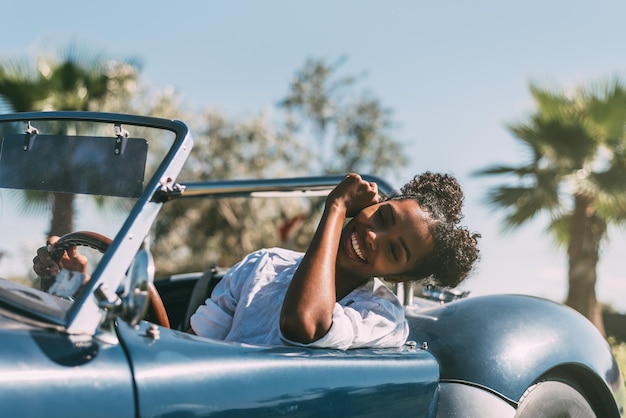 Free photo black woman driving a vintage convertible car