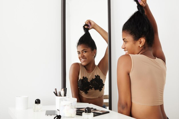 黒人女性は鏡で髪をとかすのを楽しんでいます
