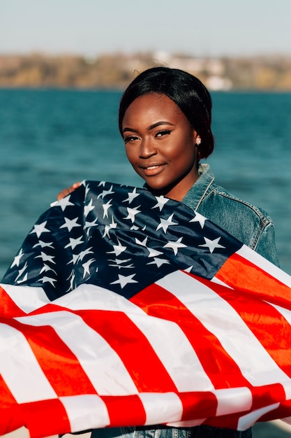 Foto gratuita bandiera americana della tenuta della donna di colore