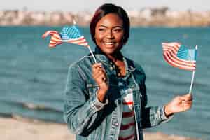 Free photo black woman holding american flags in hands