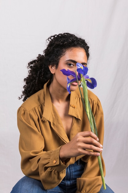 Black woman holding flower at face