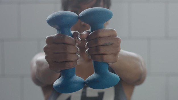 Foto gratuita ritratto di donna nera durante il primo piano di allenamento con i pesi con foucus a portata di mano con il peso che si sposta su una fotocamera