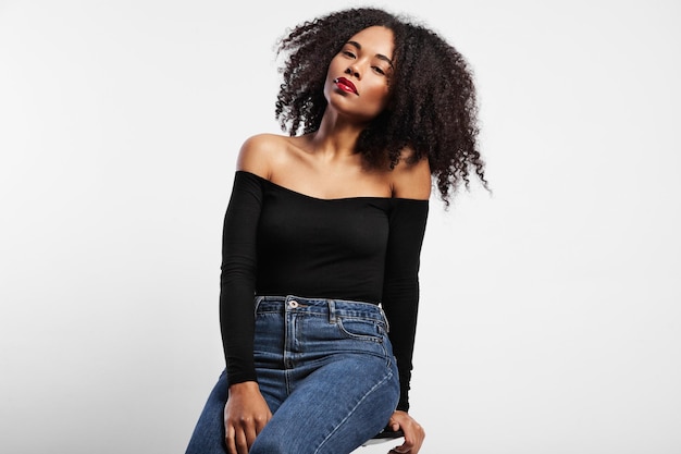 Black woman sits on the chair in studio big afro hair