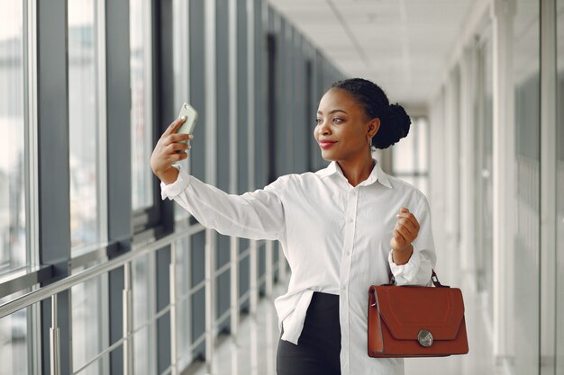 Чернокожая женщина, стоящая в офисе с ноутбуком