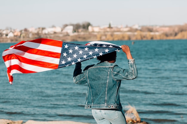 Black woman turned back holding American flag