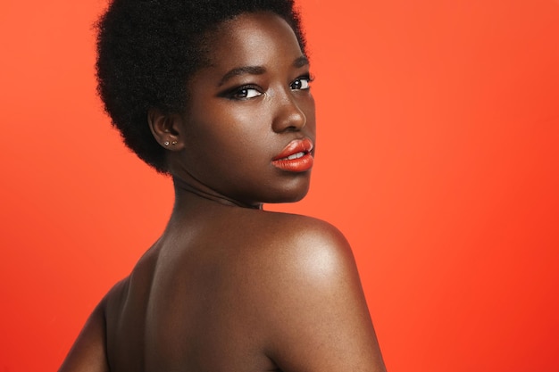 Черная женщина с яркими губами на ярко-оранжевом фоне
