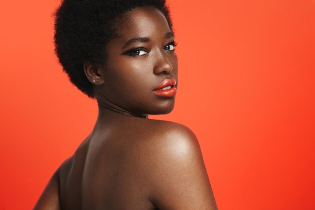 明るいオレンジ色の背景に明るい唇を身に着けている黒人女性