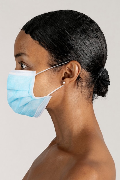 Free photo black woman wearing a surgical mask in a profile shot
