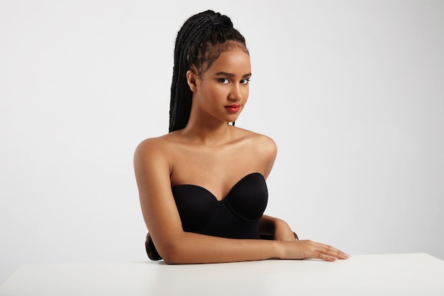 Black woman in white space in table wears braids hair