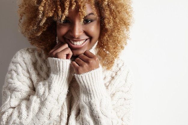 Black woman with blond curly hair wears soft sweater