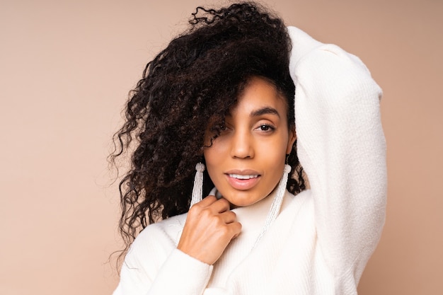 black woman with curly hairs in casual outfit posing on beige