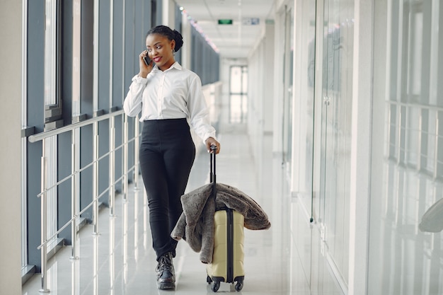 Чернокожая женщина с чемоданом в аэропорту