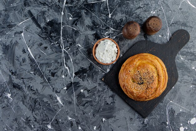 A black wooden board of Azerbaijani gohal and a clay bowl of flour 