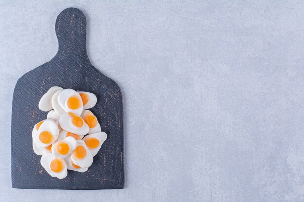 Foto gratuita una tavola di legno nera piena di uova fritte in gelatina dolci su superficie grigia