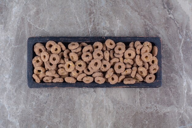 A black wooden board of healthy chocolate cereal rings for breakfast