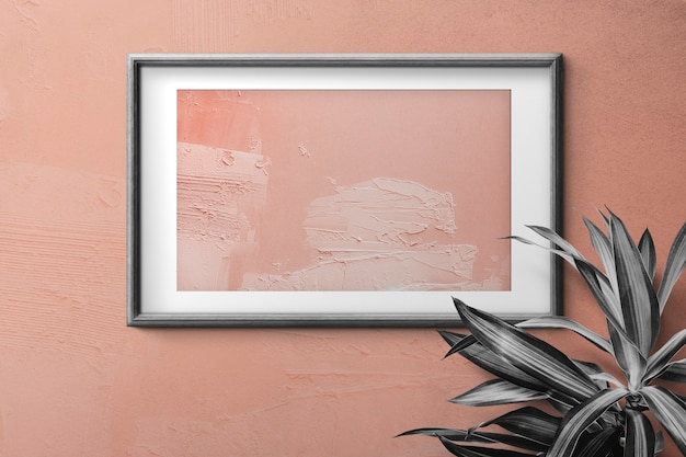 Free photo black wooden photo frame with peach color painting on wall