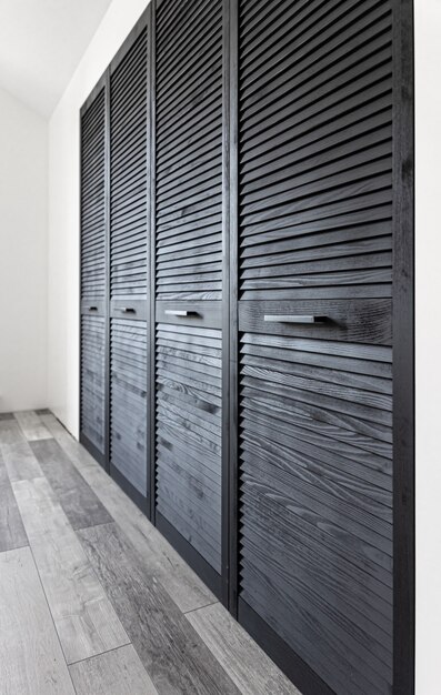 Black wooden wardrobe decorated with blinds, wardrobe with blinds decoration.