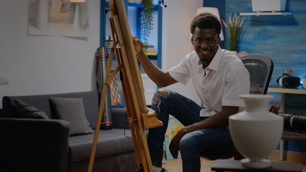 Black young adult sitting in artwork studio drawing vase