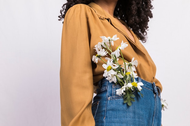 Черная молодая женщина с цветами в кармане джинсов