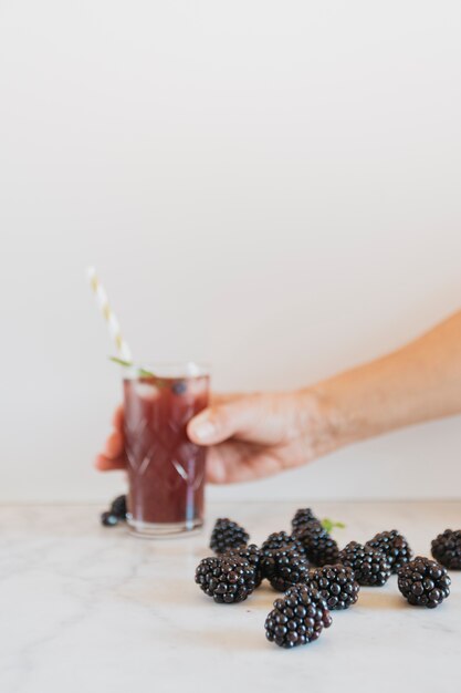 Blackberries near crop hand with glass