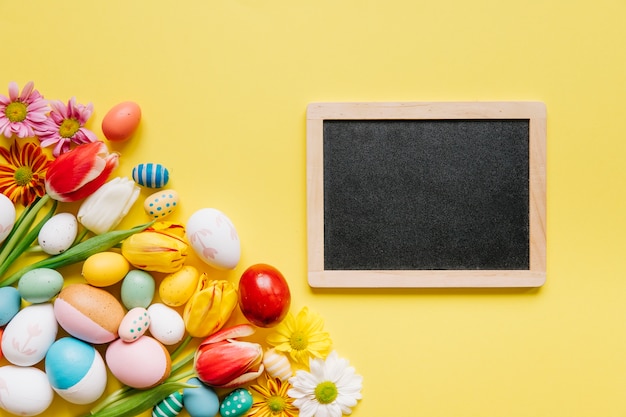 Blackboard in arrangement with flowers and eggs