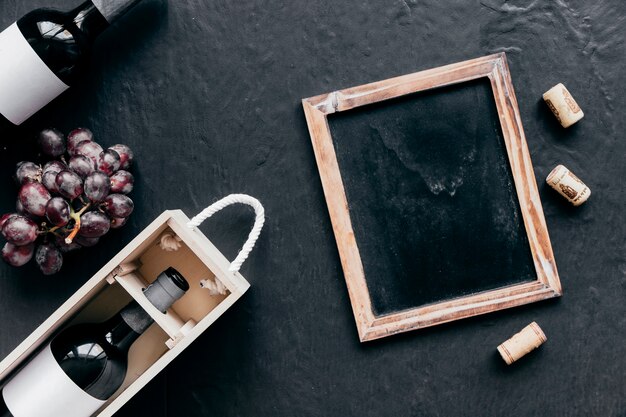 Blackboard and corks near bottles and grape