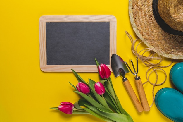 Free photo blackboard and gardening tools on yellow background