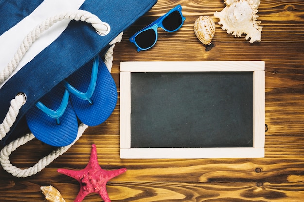 Blackboard near bag with beachwear