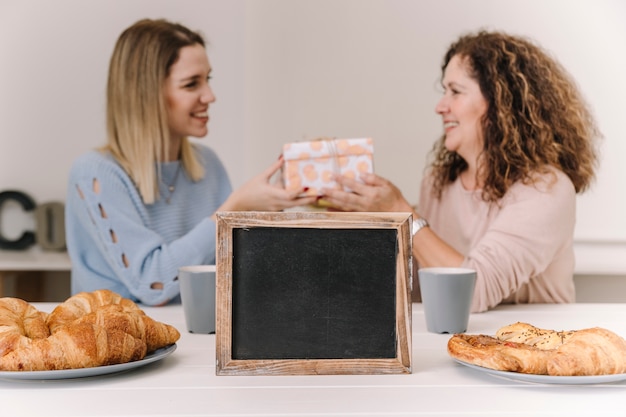 Blackboard near mother and daughter with gift