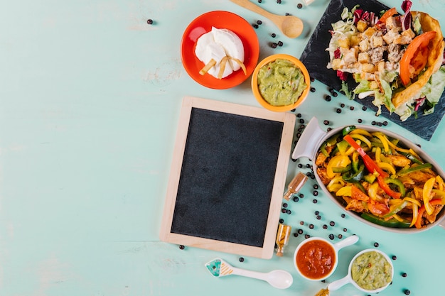 Free photo blackboard near paper and mexican dishes