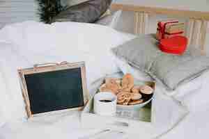 Free photo blackboard near tray and gifts on bed