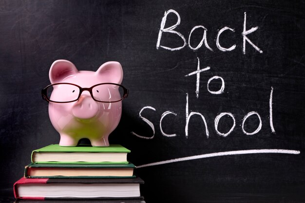 Blackboard and nice piggy on a book pile