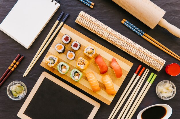 Blackboard and notebook near sushi