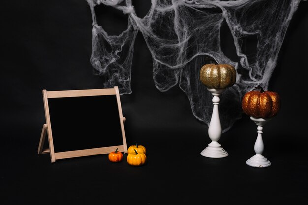 Blackboard and pumpkins near candles and web