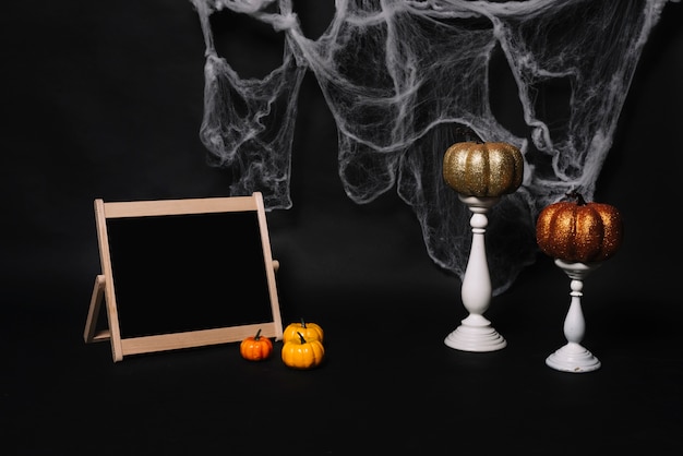 Blackboard and pumpkins near candles and web