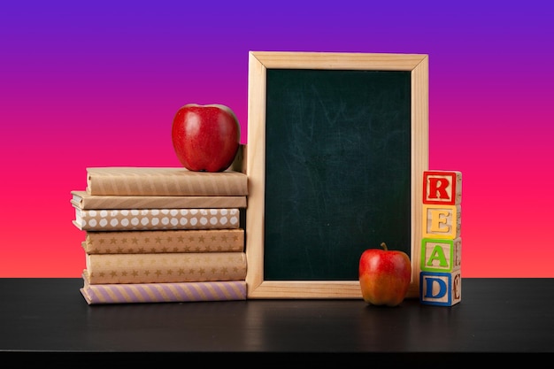 Blackboard and stacked books against colored background