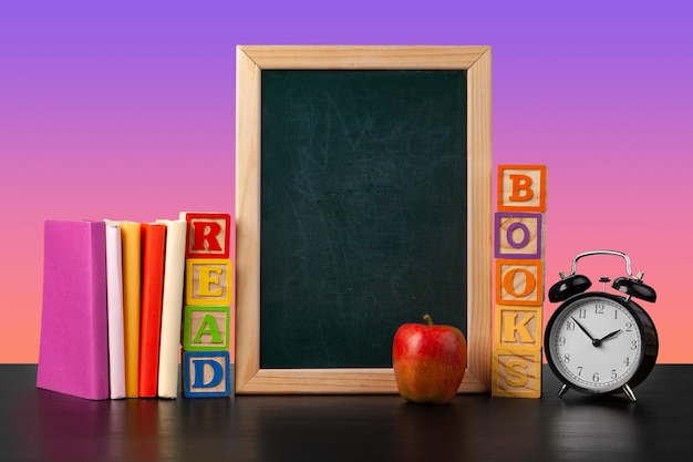 Blackboard and stacked books against colored background