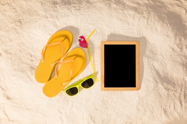 Blackboard and summer accessories on sand