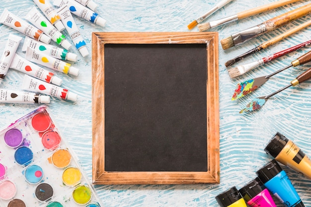 Free photo blackboard surrounded by painting material