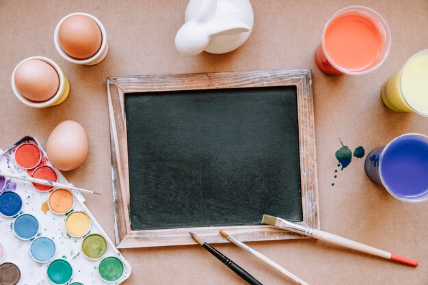 Blackboard on table with brushes and eggs