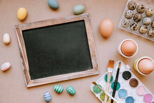 Blackboard on table with colorful Easter eggs