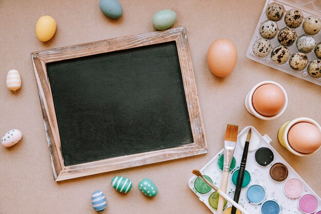 Blackboard on table with colorful Easter eggs