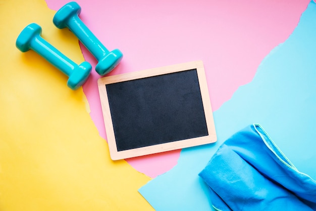 Free photo blackboard between towel and dumbbells