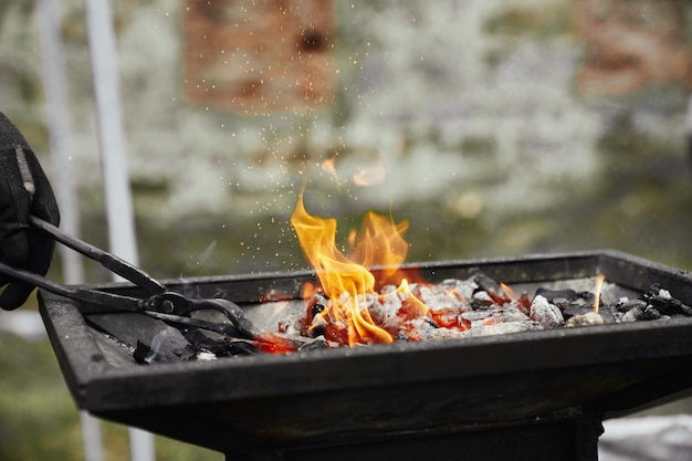 Free photo blacksmith heating metal piece in burning coal