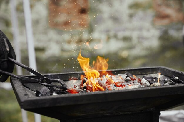 Blacksmith heating metal piece in burning coal