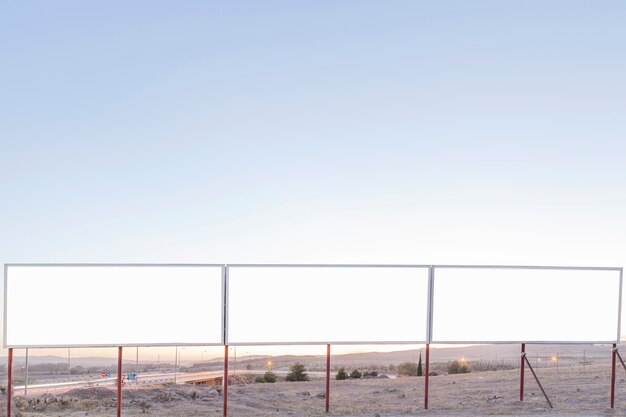 Blank advertising billboards near the highway against blue sky