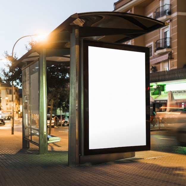 Blank billboard on bus stop shelter at night