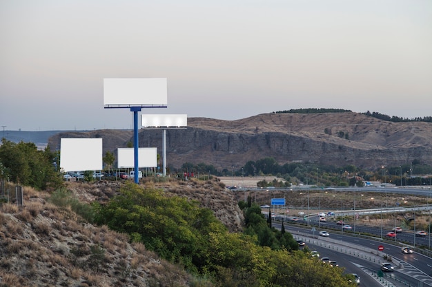高速道路の近くの山の新しい広告のためのブランクの掲示板