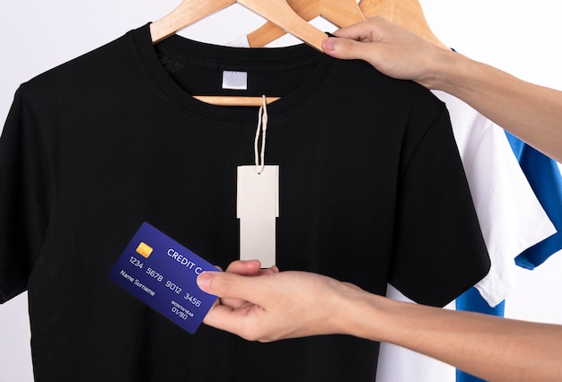 blank black t-shirt and blank label tag for advertising. Hand holding credit card for shopping for shirt.